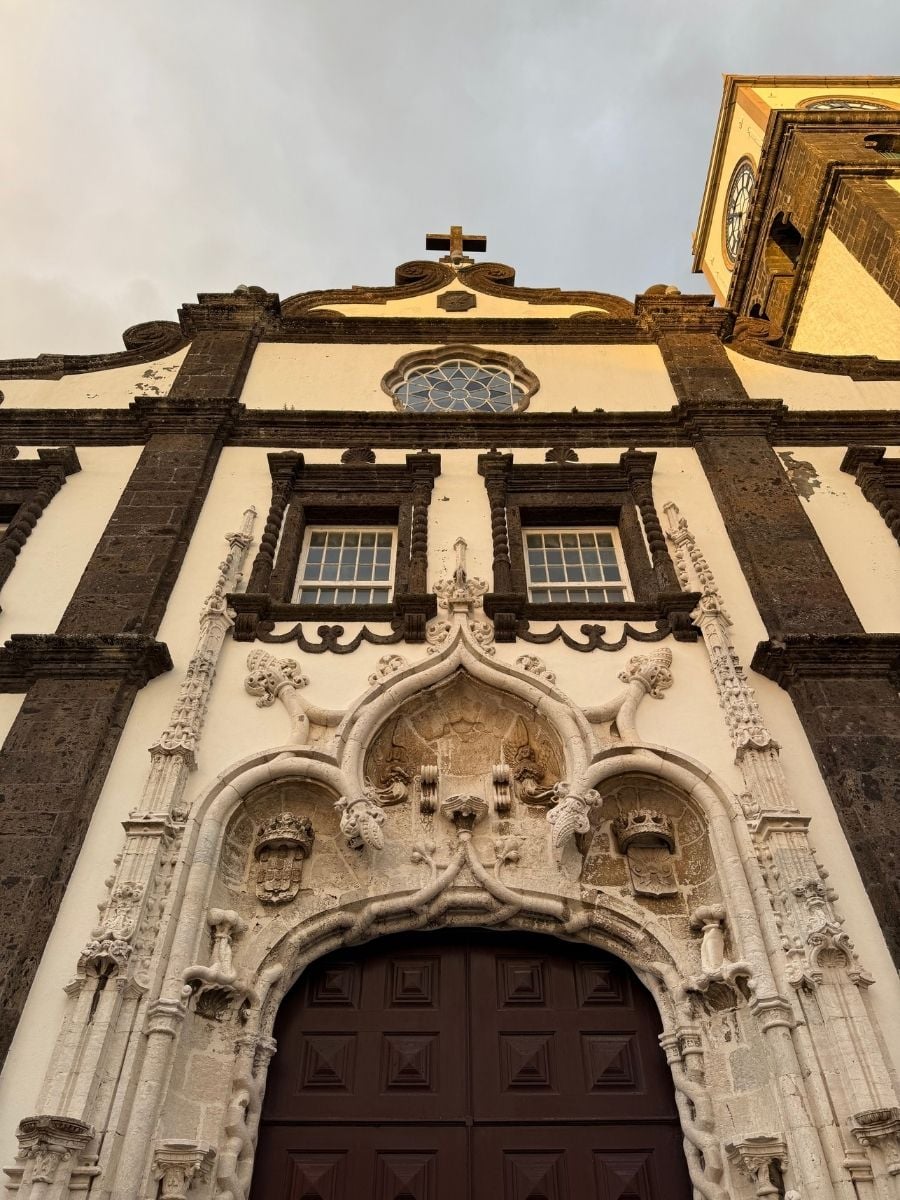 Historic church facade with detailed stonework and a clock tower in S&atilde;o Miguel, Azores under dramatic evening light