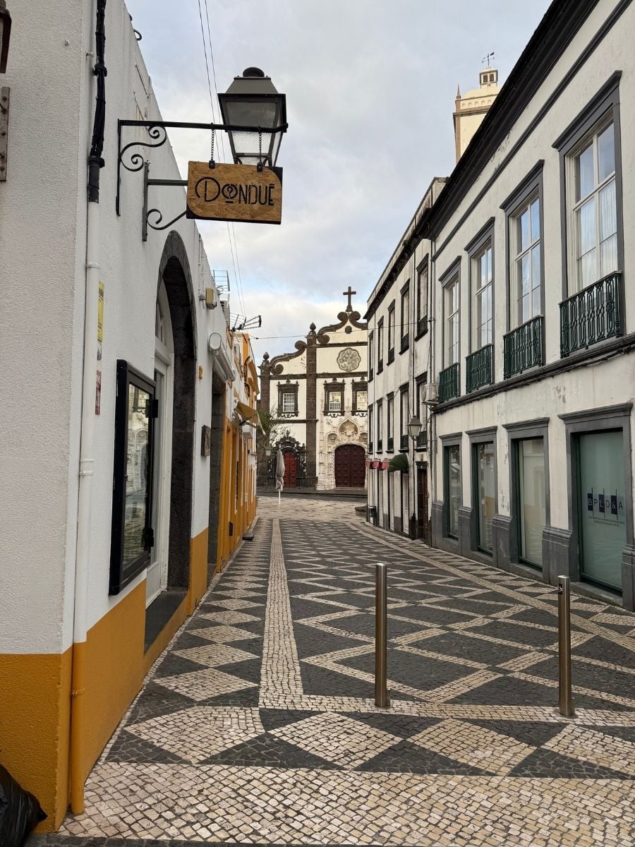 Charming cobblestone street leading to a historic church in Ponta Delgada, S&atilde;o Miguel, Azores with traditional buildings and balconies
