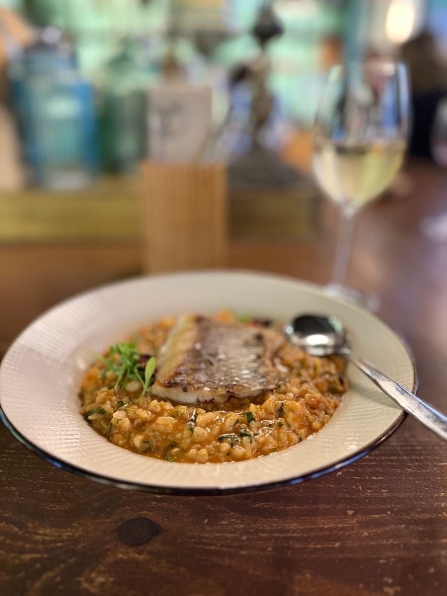 Seafood rice dish topped with grilled fish served with white wine in a restaurant in S&atilde;o Miguel, Azores