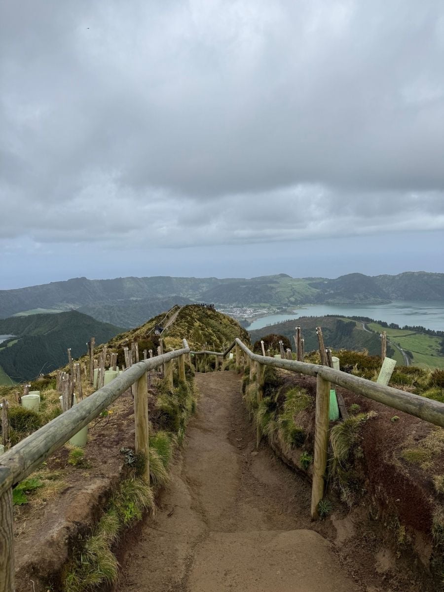 Narrow hiking trail with wooden railings overlooking Sete Cidades lakes in S&atilde;o Miguel, Azores under low hanging clouds