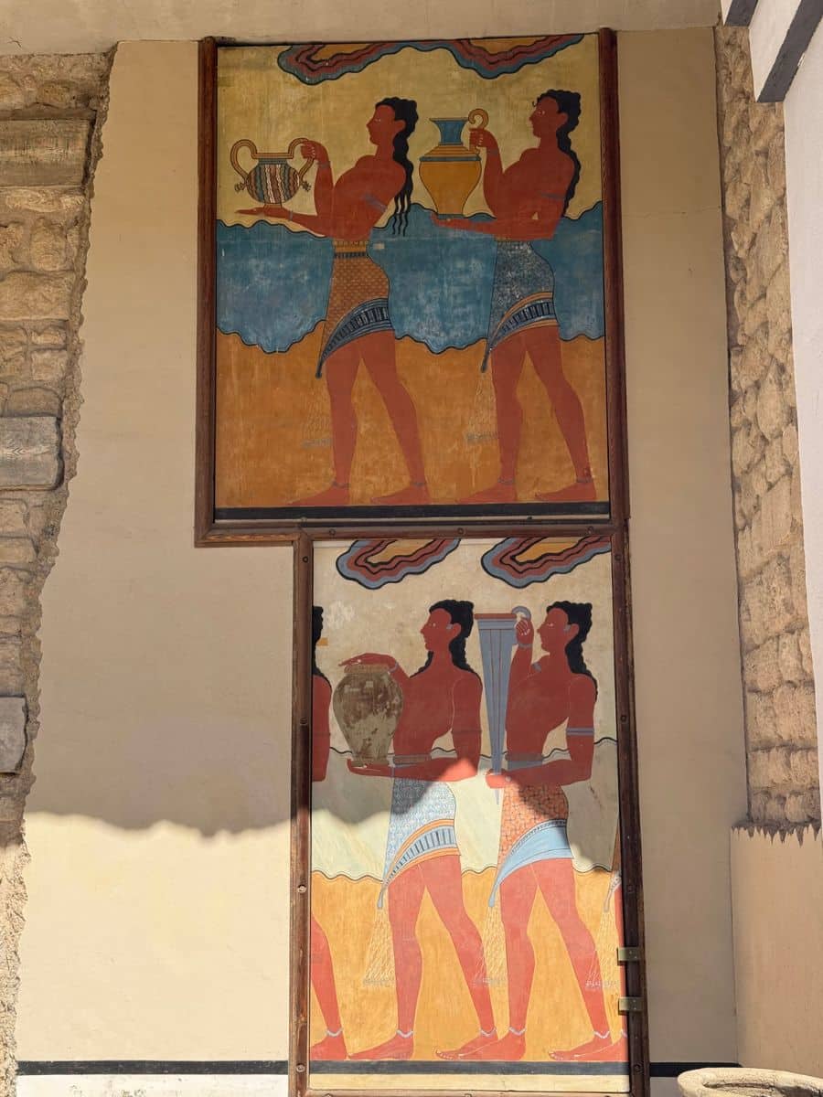 Close-up of reconstructed Minoan frescoes showing ceremonial figures carrying offerings at the Palace of Knossos.