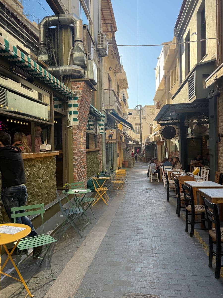Charming pedestrian street lined with cafés, restaurants, and outdoor seating in the old town of Heraklion, Crete.