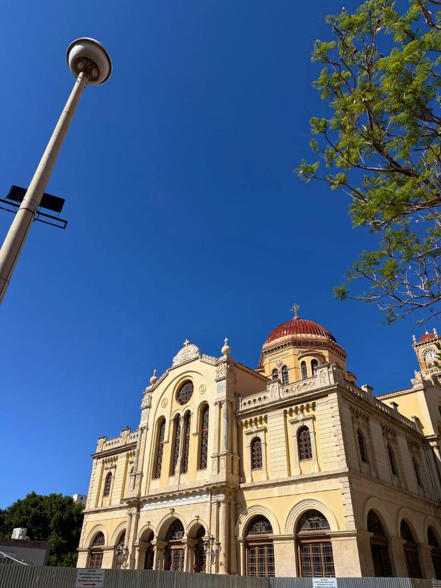 The Cathedral of Saint Minas in Heraklion, Crete, illuminated by bright Mediterranean sunshine against a clear blue sky.