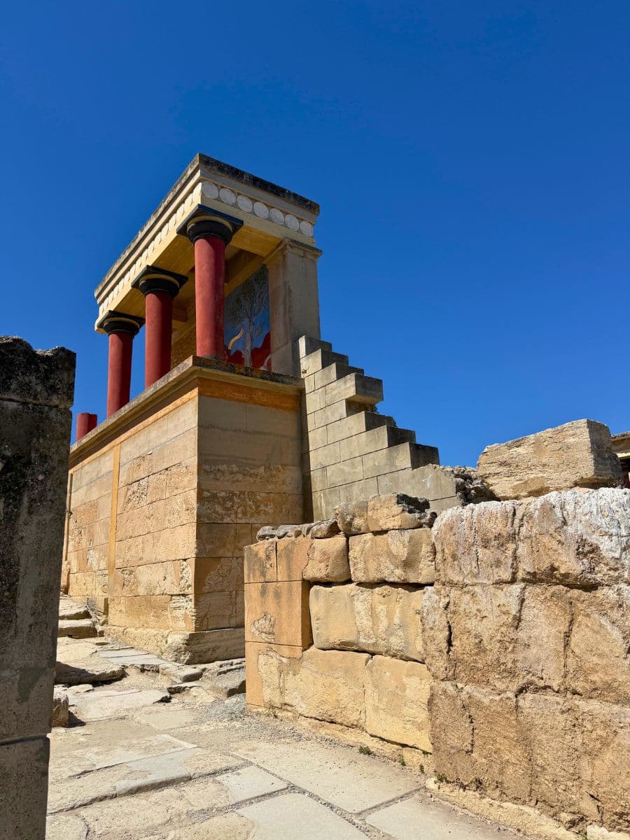 The restored North Entrance of the Palace of Knossos archaeological site near Heraklion, Crete, under a clear blue sky.