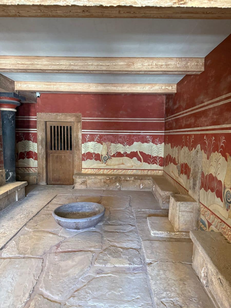 The Throne Room at the Palace of Knossos featuring reconstructed Minoan frescoes and ancient stone seating in Crete.