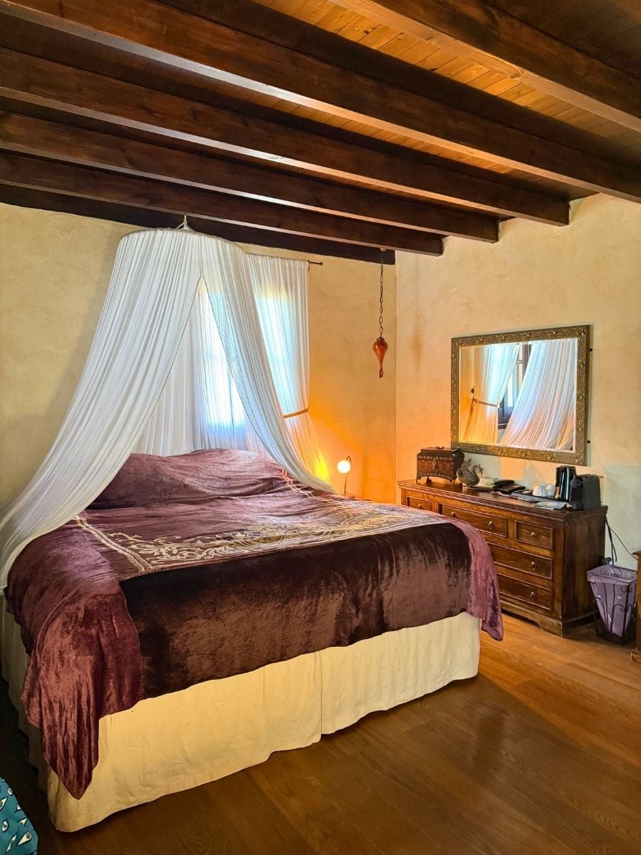 Elegant bedroom with a canopy bed, exposed wooden beams, and classic furnishings in Rhodes Old Town, Rhodes, Greece.