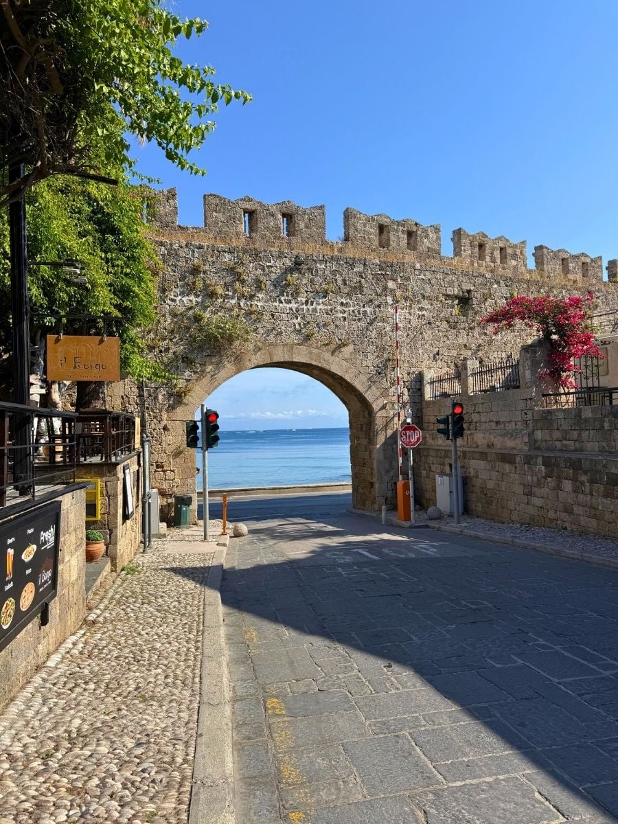 Medieval stone gate opening toward the sea along the fortified walls of Rhodes Old Town, Rhodes, Greece.
