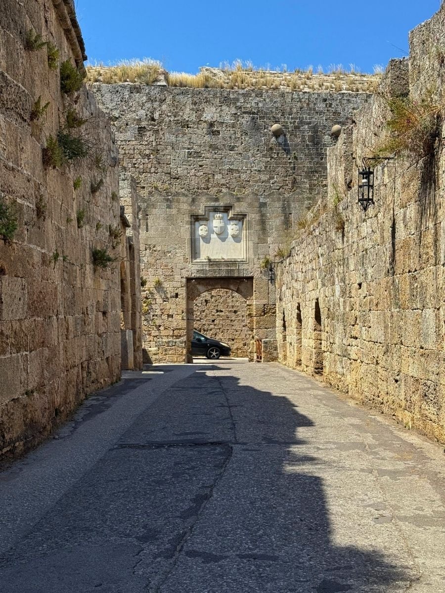 Historic stone gateway framed by towering medieval walls in Rhodes Old Town, Rhodes, Greece.
