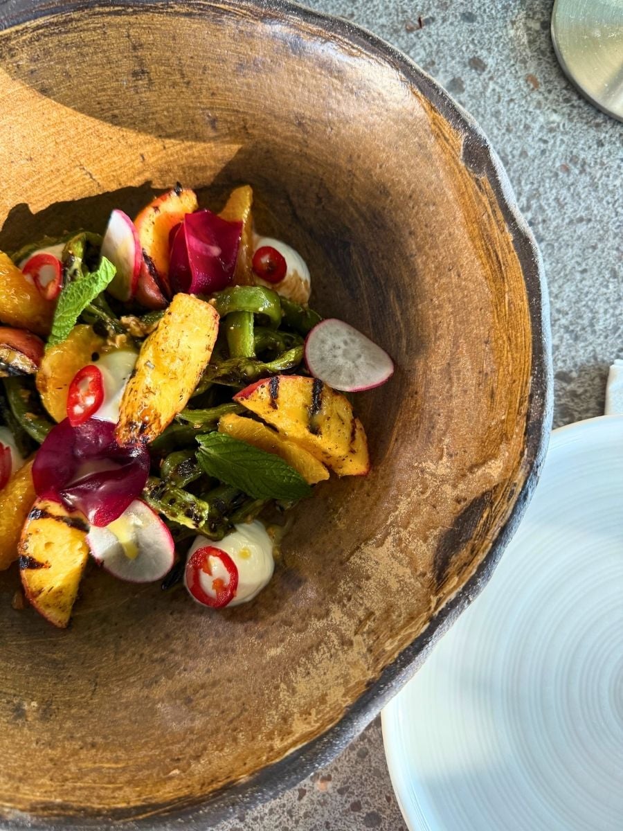 Grilled peach and charred asparagus salad with citrus, radish, herbs, and creamy dressing served in Rhodes, Greece.