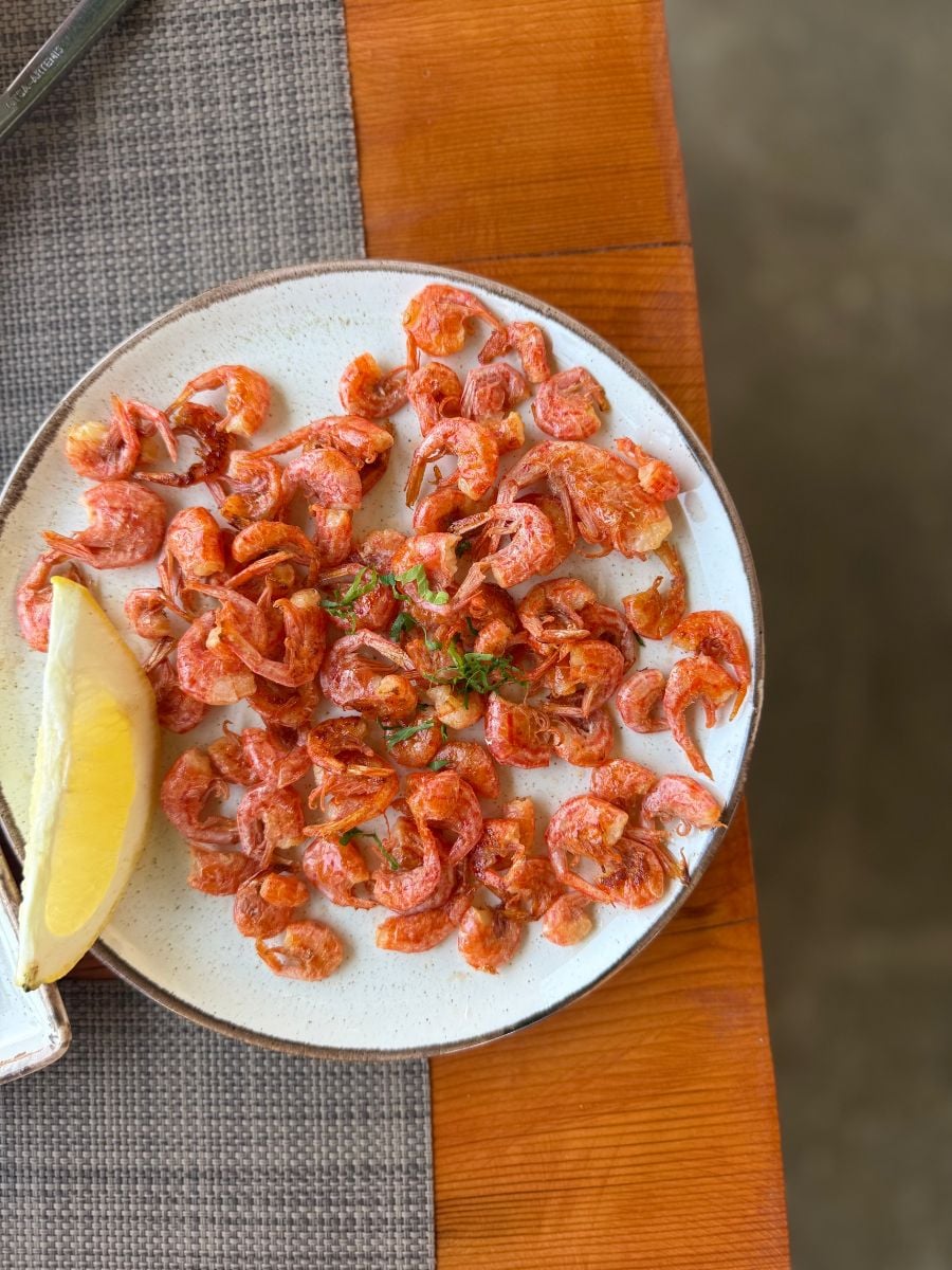 Plate of crispy fried Symi shrimp served with fresh lemon at Kali Strata Restaurant in Symi, Greece.
